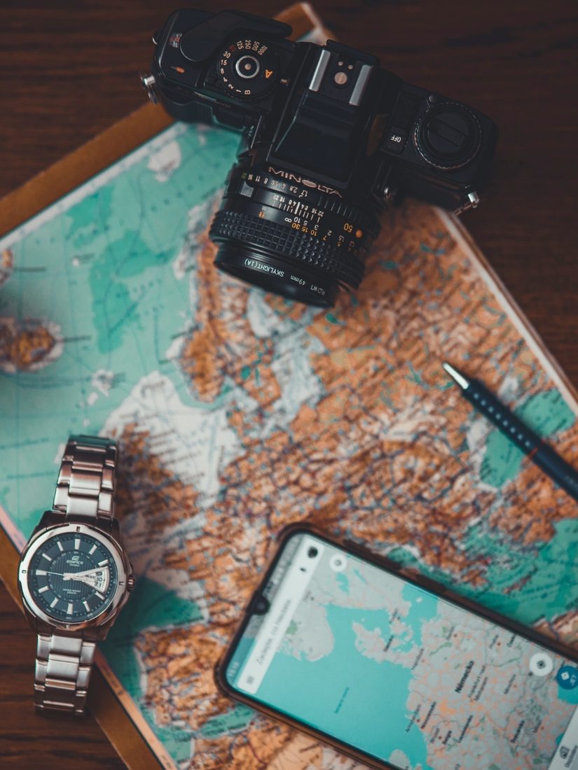 Travel flat-lay with a camera, watch, phone and world map